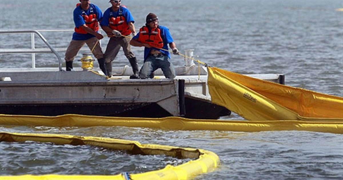 Рятувальники розтягують у воді спеціальні загороджувальні бони, щоб захистити узбережжя від нафти. / © AFP