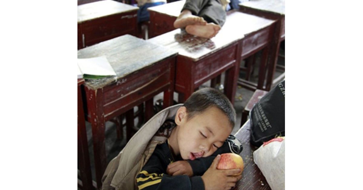 Родини, які були евакуйовані з долини ріки Фу через повінь, сплять у класній кімнаті однієї зі шкіл Фучжоу. Китайським рятувальникам довелося евакуювати більше 120 тисяч людей через прорив дамби на ріці Фу. Повінь у Китаї вже забрала життя 200 людей. / © AFP