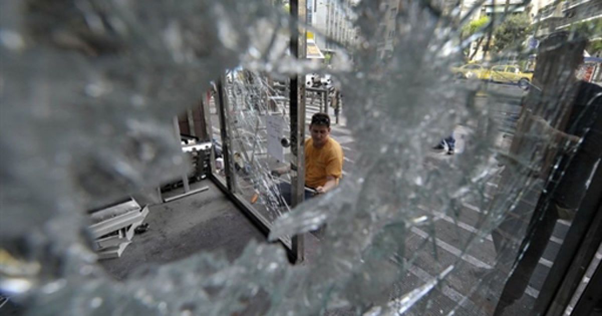 Комунальний співробітник замінює вікна, які побили демонстранти, у будинку міської адміністрації Афін. Грецію захлиснула чергова хвиля протестів. Вчора від вибуху гранати демонстрантів загинули троє людей. / © AFP