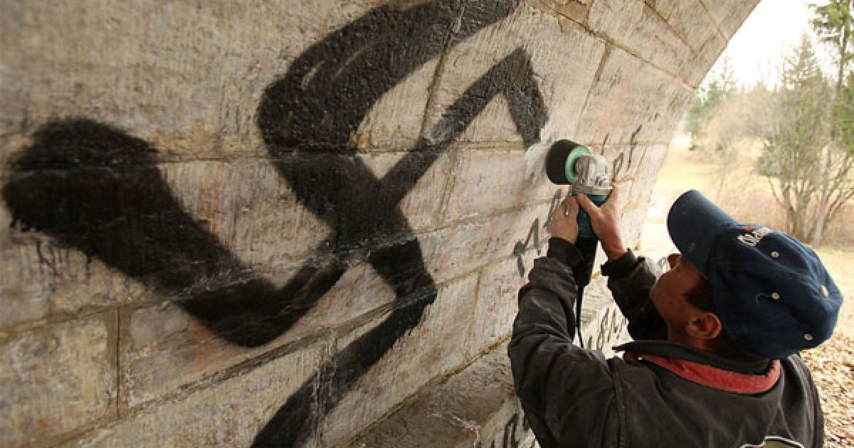 Росія. Працівник муніципальної служи зчищає свастики і цитати Адольфа Гітлера зі стіни у історичному палацово-парковому комплексі Павловськ під Санкт-Петербургом. Міліція заарештувала декілька молодих людей, яких підозрюють у скоєнні акту вандалізму. / © AFP