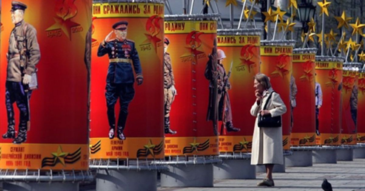Жінка роздивляється святкові плакати, присвячені Дню перемоги, у Москві. / © AFP