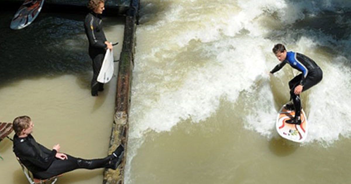Німеччина, Мюнхен. Серфер катається на хвилях каналу "Eisbach" у Англійському саду (Мюнхен). Температура у Баварії піднялась до 26 градусів за Цельсієм. / © AFP