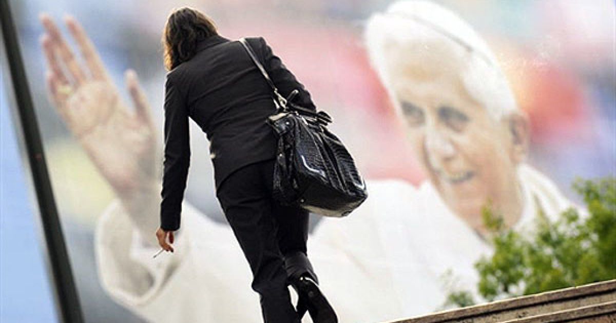 Португалія, Лісабон. Жінка проходить поруч із плакатом, на якому зображено Папу Римського Бенедикта XVI, напередодні офіційного візиту Папи Бенедикта XVI до Португалії. / © AFP