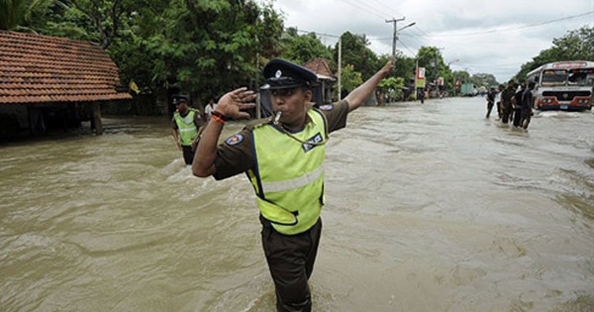 Шрі-Ланки, Коломбо. Поліцейський регулює дорожній рух на затопленій вулиці у передмісті Коломбо. Сильні мусонні дощі, які не вщухали протягом 4 днів, спричинили повінь у країні. В результаті розгулу стихії загинуло 17 людей, більше 400 тисяч були змушені залишити свої домівки. Найбільше постраждала від мусону столиця Шрі-Ланки Коломбо, водою розмило під&#039;їзні шляхи до аеропорту. / © AFP