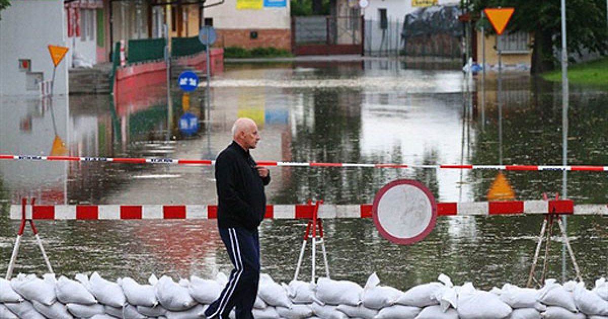 Польща, Кросно Одржаньске. Місцевий житель проходить повз затоплену вулицю, перекриту мішками з піском, у селищі Кросно Одржаньске поруч із німецьким кордоном.  У Німеччині Центр зі спостереження за повенями оголосив у федеральній землі Бранденбург вищий стан готовності до стихійного лиха у зв'язку з імовірністю сильної повені. / © AFP