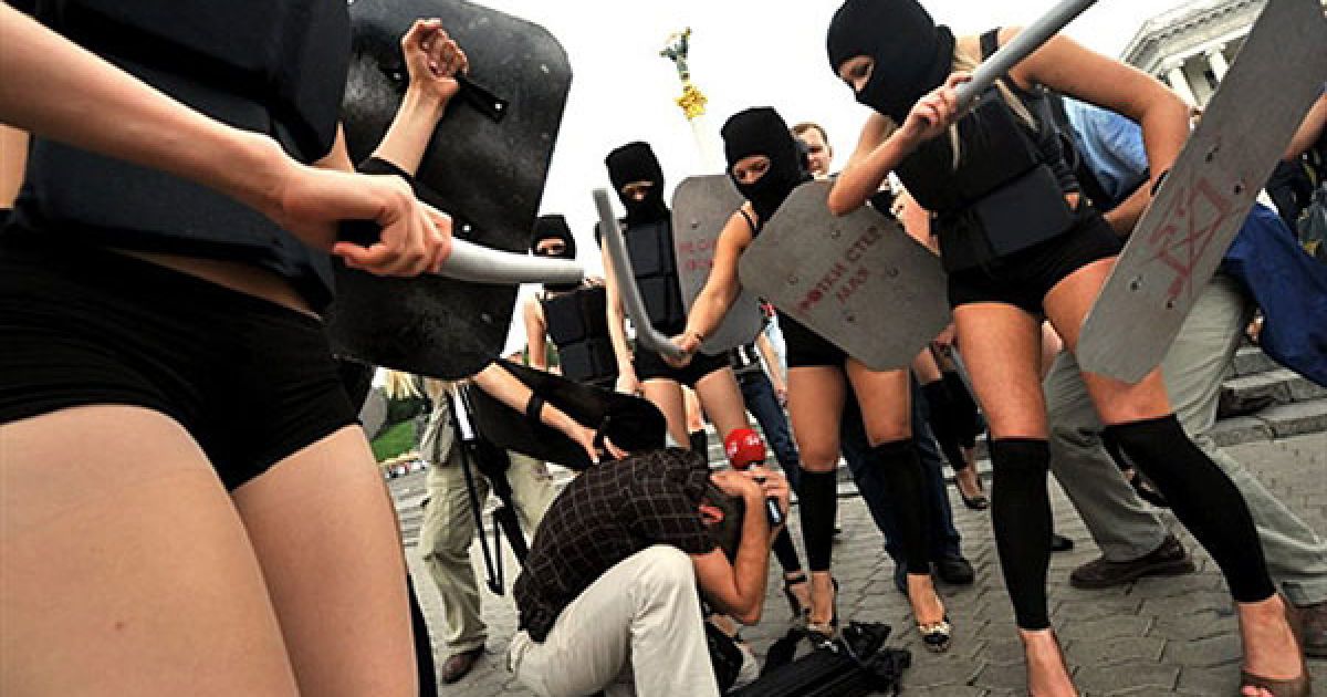 Україна, Київ. Активістки жіночого руху "FEMEN", одягнені у "спецназівську" форму провели на Майдані Незалежності акцію "100 днів: Я тобі твою камеру в дупу засуну!", приурочену до перших 100 днів президентства Віктора Януколвича. Під час акції дівчата били поролоновими дубцями журналістів, фотографів та операторів. FEMEN протестував проти обмеження демократичних свобод і свободи преси. / © AFP
