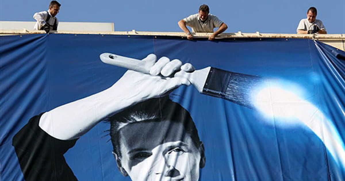 Франція, Канни. Робочі закріпляють рекламний плакат 63-го Каннського кінофестивалю на фасаді Палацу фестивалів. На плакаті зображено французьку актрису Жюльєтт Бінош. / © AFP