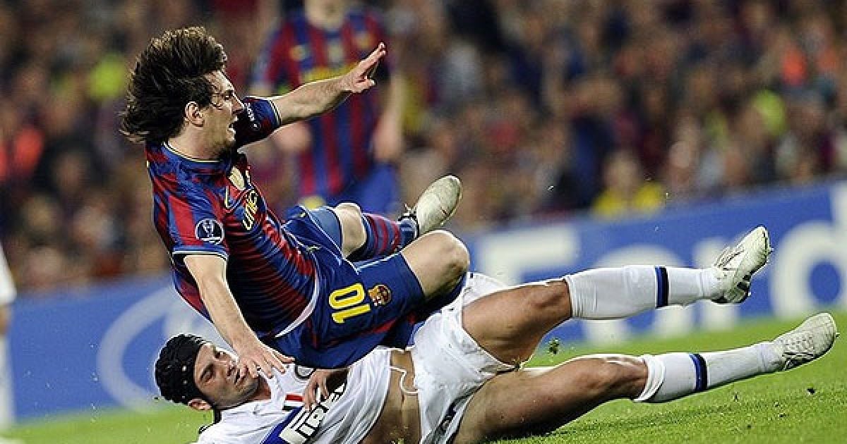 Крістіан Чіву ("Інтер") збиває з ніг Лео Мессі ("Барселона"). / © AFP