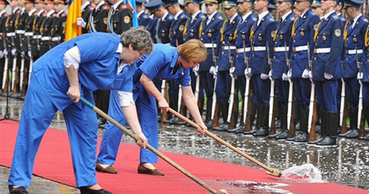 Україна, Київ. Прибиральниці змітають воду з килима після сильного дощу. Зустріч російського президента Дмитра Мєдвєдєва з його українським колегою пройшла під проливним дощем. Дмитро Медведєв прибув до України з офіційним дводенним візитом. / © AFP