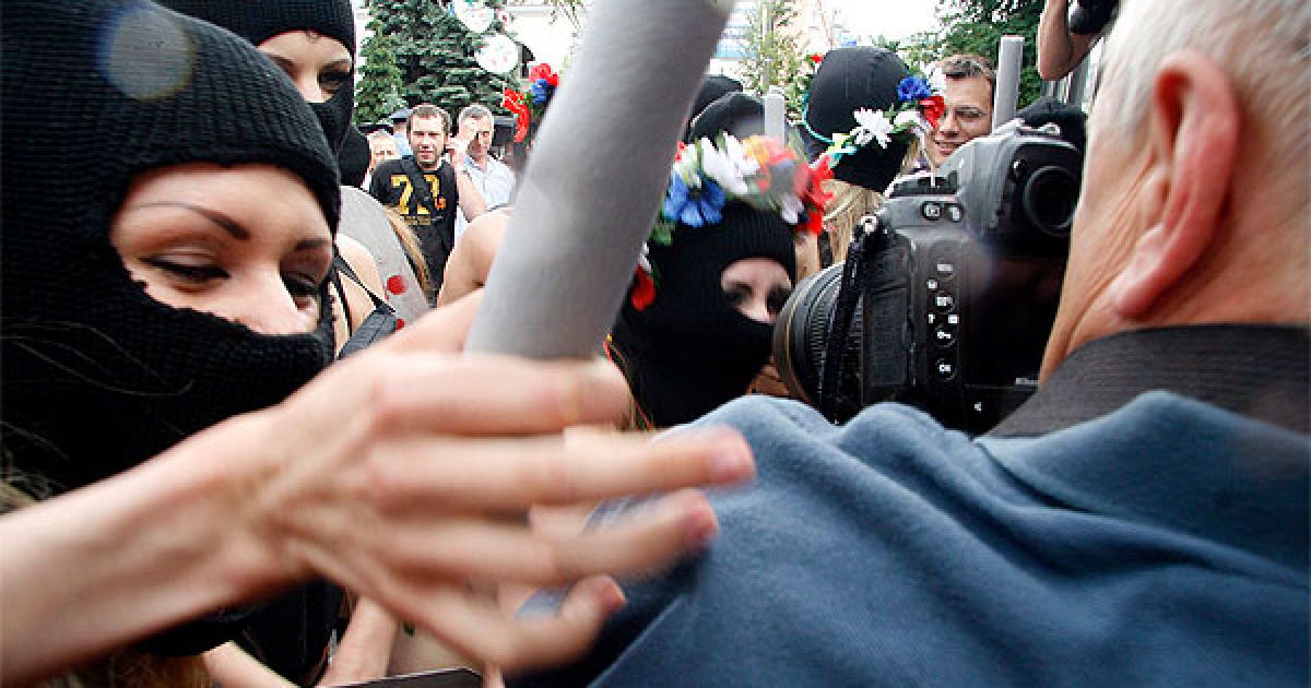 Активістки FEMEN вийшли на акцію у чорних костюмах, накшталт спецназівських, масках і з криками "Забери камеру!", "Не знімати, твою мать!" накинулися на журналістів і фотографів із поролоновими дубцями. / © Жіночий рух FEMEN