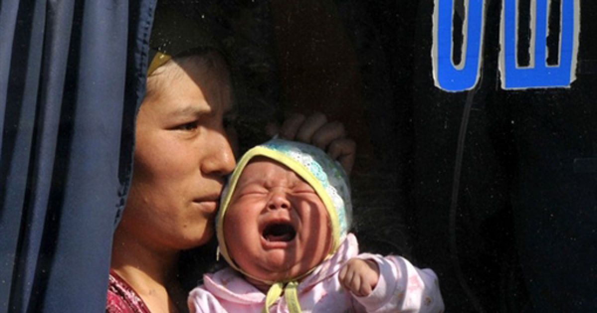 Жінка сидить із соєю дитиною у автобусі із написом "Ош" на вікні. За повідомленнями киргизької влади, більше половини узбеків, які втекли з Киргизстану під час заворушень, вже повернулися до своїх домівок.