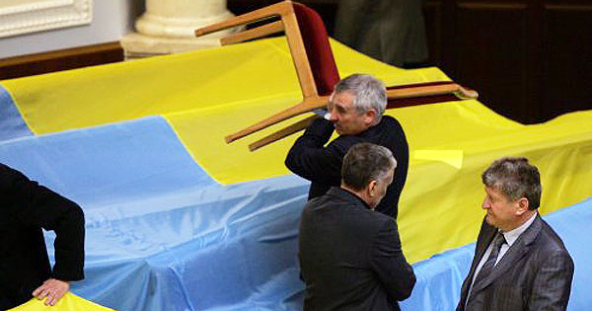 Опозиціонери накрили місця депутатів від БЮТ і НУ-НС великими державними прапорами і плакатом "Державній зраді - НІ". / © УНІАН