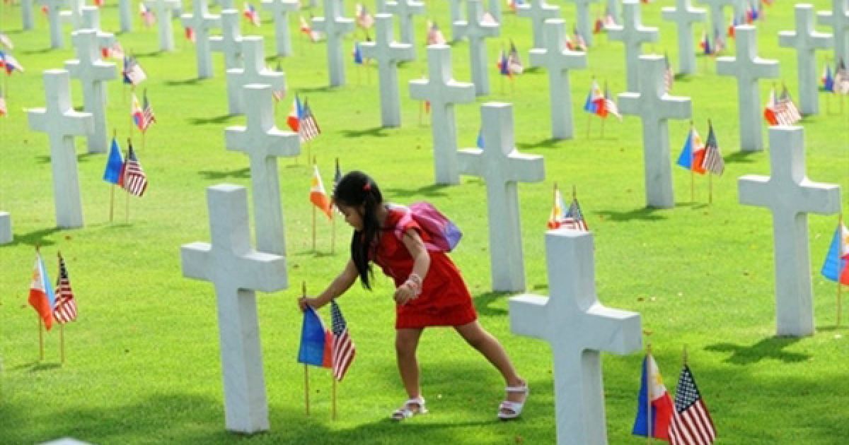 Філіппіни, Маніла. Дитина встановлює філіппінський прапор поряд із американським прапором на могилі солдата, який загинув під час Другої світової війни. У США та інших країнах відзначили День пам&rsquo;яті. Принаймні, 17 тисяч американських солдатів поховані у меморіальному парку у Форті Боніфаціо. / © AFP