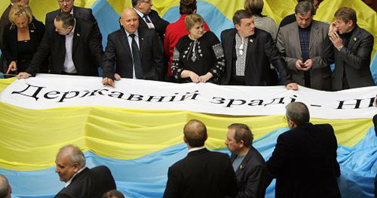 Опозиціонери накрили місця депутатів від БЮТ і НУ-НС великими державними прапорами і плакатом "Державній зраді - НІ". / © УНІАН
