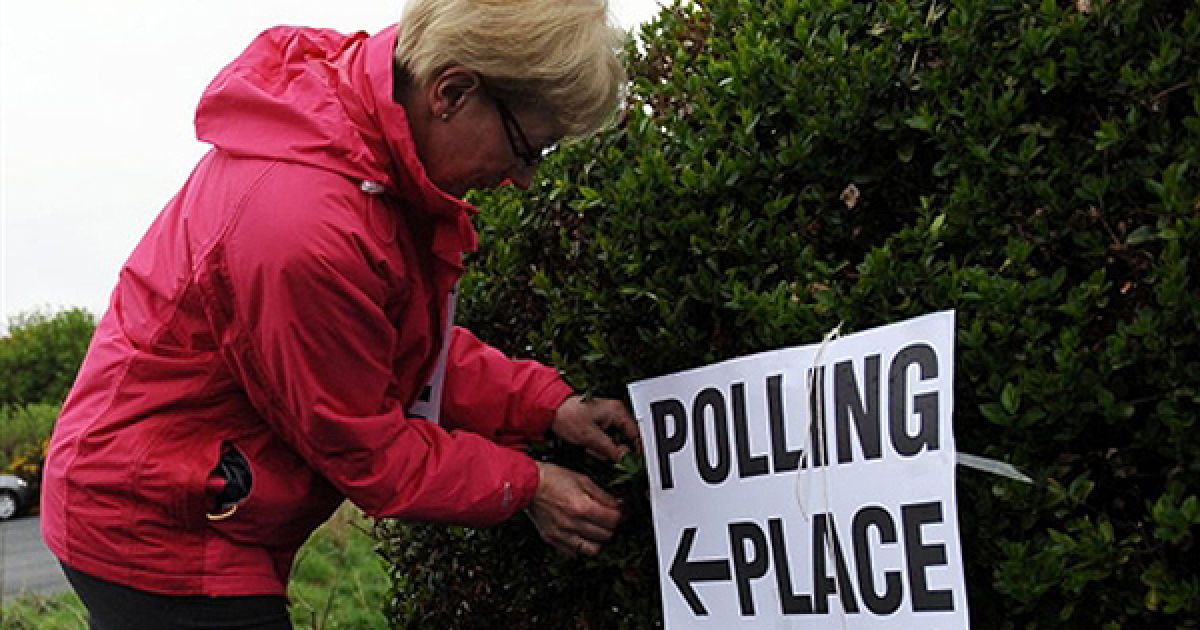 Жінка лагодить табличку виборчої дільниці у Куінсберрі, Шотландія. Сьогодні у Сполученому королівстві відбулися парламентські вибори. / © AFP