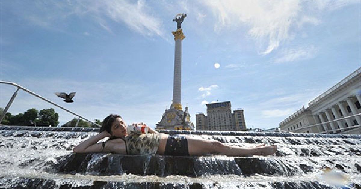 Україна, Київ. Дівчина лежить у фонтані на Майдані Незалежності у Києві. Денна температура повітря у Києві сягла 34 градусів за Цельсієм. / © AFP