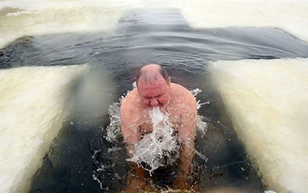 Росія, Санкт-Петербург. Православний віруючий занурюється у крижану воду під час купання на свято Хрещення Господнього (Водохреща) у Колпіно, поблизу із Санкт-Петербургом. / © AFP