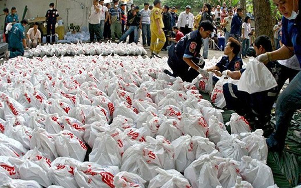 Таїланд, Бангкок. Члени Фонду порятунку несуть сумки з трупами до моргу в буддійському храмі у Бангкоку. В храмі тайська поліція знайшла людські залишки, приховані працівниками нелегальних клінік абортів у Бангкоку. Представники поліції знайшли більше 1000 трупів і заявили, що очікують подальші жахливі знахідки. / © AFP