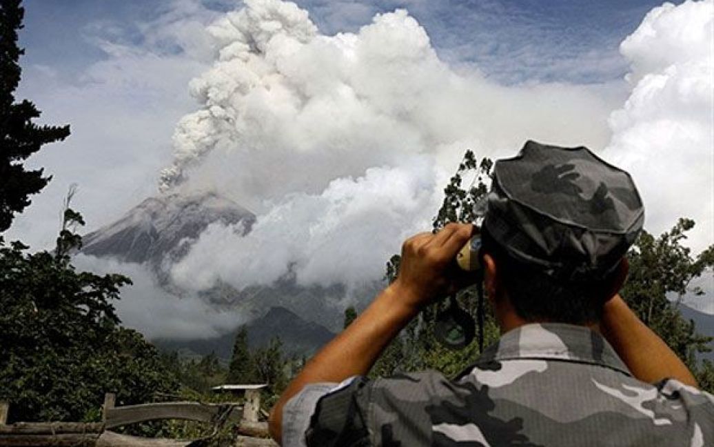 Еквадор, Пеніпе. Поліцейський роздивляється у бінокль вулкан Тунгурахуа після того, як влада наказала провести превентивну евакуацію населення з Пеніпе на південі Еквадору. Країна перебуває у стані підвищеної готовності через можливе виверження вулкана Тунгурахуа. / © AFP
