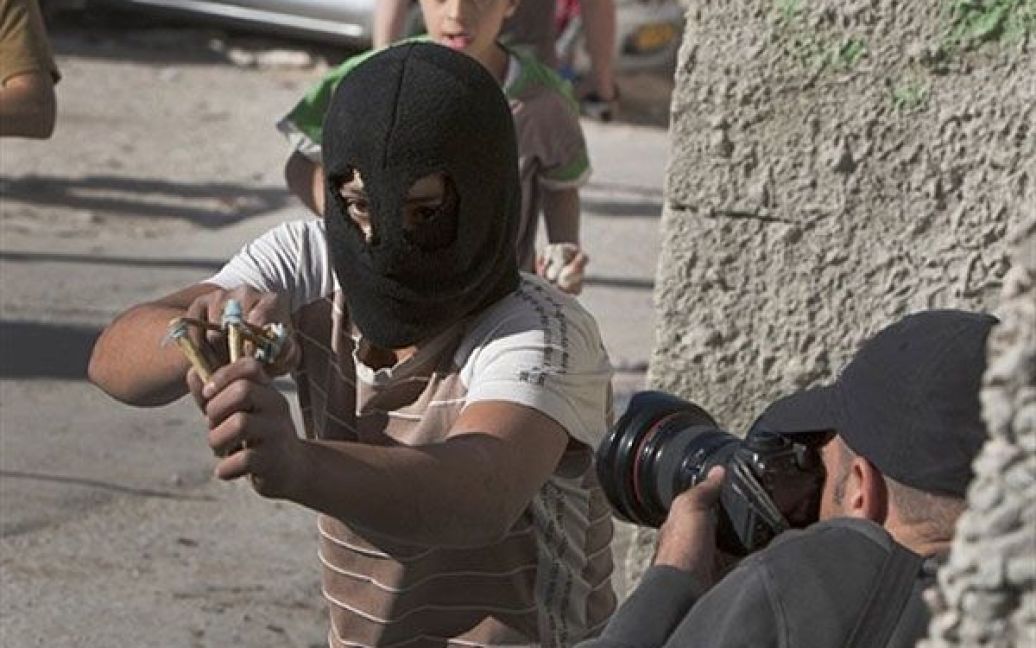 Єрусалим. Фотограф знімає, як палестинський юнак стріляє з рогатки під
час сутичок з ізраїльською поліцією у кварталі Сильван, Східний
Єрусалим. / © AFP