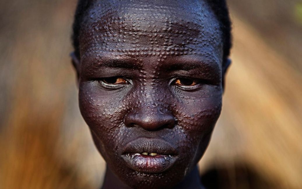Жінка з суданського племені Нуер з традиційним для цього племені шрамуванням на обличчі стоїть перед своєю хатиною у місті Малакал. (REUTERS / Finbarr O&#039;Reilly) / © The Boston Globe