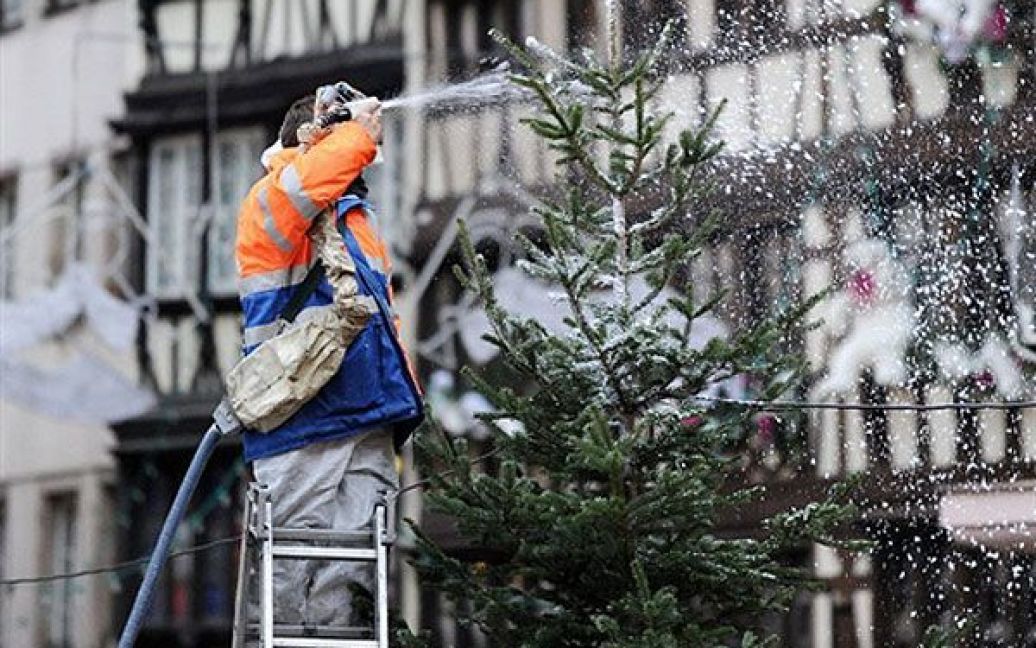 Франція, Страсбург. Чоловік розпилює штучний сніг на новорічні ялинки на вулиці Страсбурга напередодні відкриття відомого різдвяного базару. Очікується, що цього року майже два мільйони відвідувачів візьмуть участь у ярмарку Christkindelsmarik. / © AFP