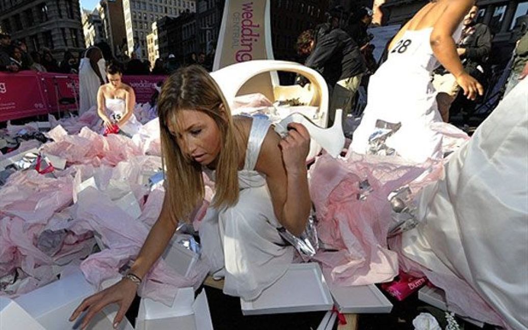 США, Нью-Йорк. Наречені намагаються знайти дизайнерське взуття серед сотень взуттєвих коробок під час весільного змагання "Якщо взуття підходить" у парку Медісон-сквер (Нью-Йорк). / © AFP