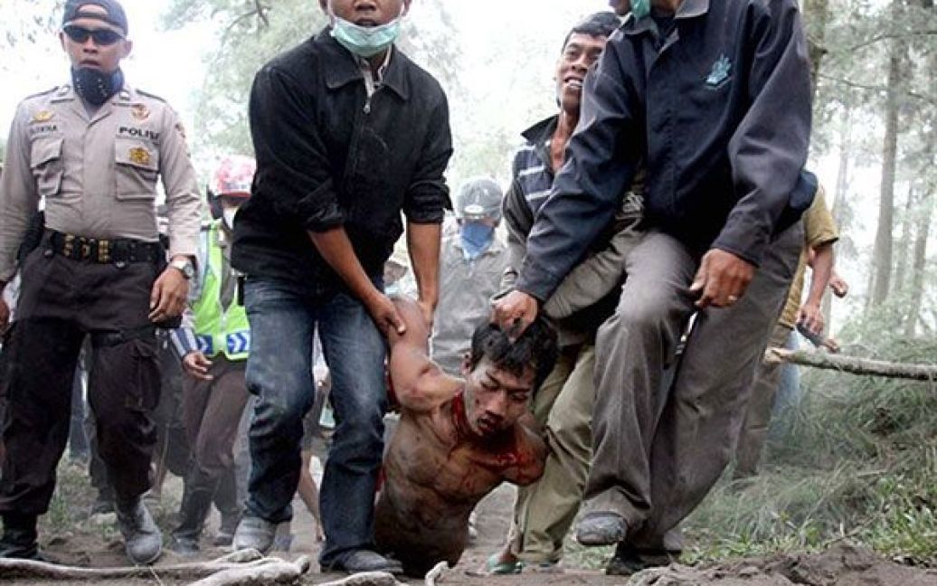 Індонезія. Мешканці села у супроводі поліції несуть підозрюваного у пограбуванні, якого вони зловили у покинутому селищі Слеман, що знаходиться у небезпечній зоні вулкана Мерапі. Найактивніший вулкан Індонезії продовжує викидати великі хмари гарячого газу і попелу, в результаті загинули щонайменше 36 людей. / © AFP