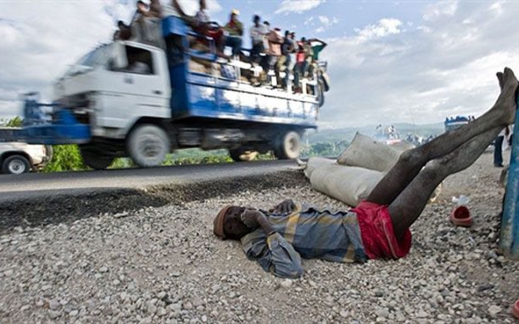 Гаїті, Понт-Сонде. Чоловік, хворий на холеру лежить на узбіччі дороги у Понт-Сонде. Він раптом впав посеред ринку на мосту через річку Артібоніт, вода якої вважається джерелом спалаху холери у Гаїті. Свідки підтвердили, що він пив воду з річки. / © AFP
