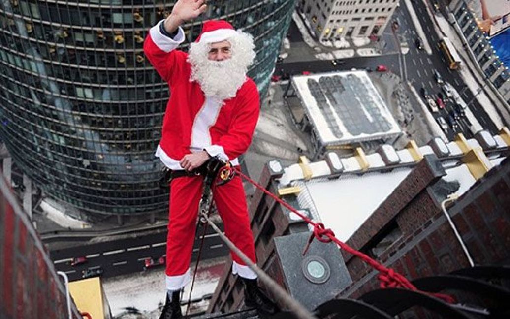 Німеччина, Берлін. Альпініст у костюмі Санта Клауса готується до спуску зі 100-метрової Kollhoff-Tower на Потсдамській площі в Берліні. / © AFP