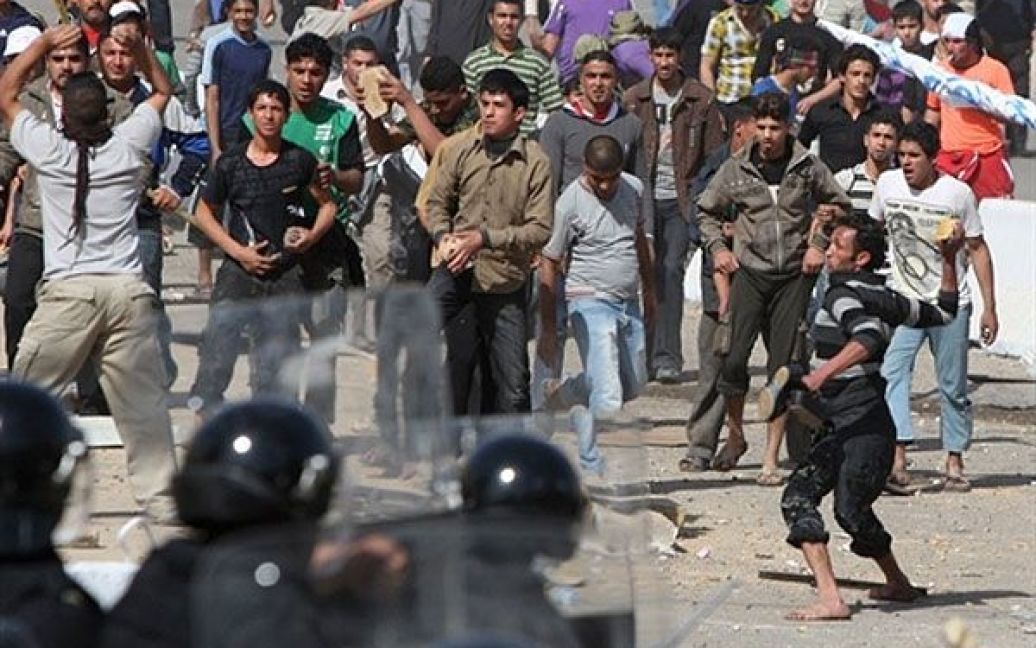 Ірак, Багдад. Іракські демонстранти кидають каміння у поліцейських під час протестів на центральній площі Багдада. Протестувальники вимагають поліпшення державних послуг, збільшення кількості робочих місць і зниження рівня корупції у країні. Під час зіткнень з поліцією на День гніву в Іраку загинули сім осіб. / © AFP