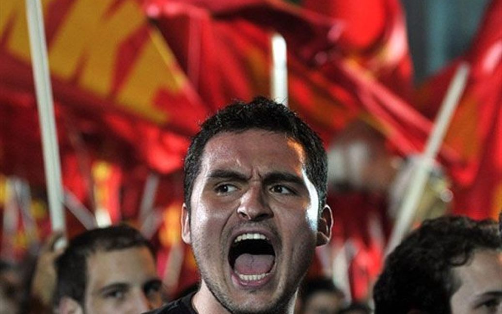 Греція, Афіни. Прихильник комуністичної партії вигукує гасла під час акції протесту в центрі Афін, яку влаштували проти візиту трійки МВФ-ЄС до Афін і прийняття нового "пакету" жорсткої економії для Греції. / © AFP