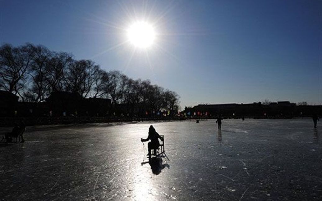 Китай, Пекін. Люди катаються на ковзанах по замерзлому озеру у центрі Пекіна. Надзвичайно холодна погода у південній та центральній частині Китаю змусила провести екстрену евакуацію майже 60 тисяч людей. / © AFP