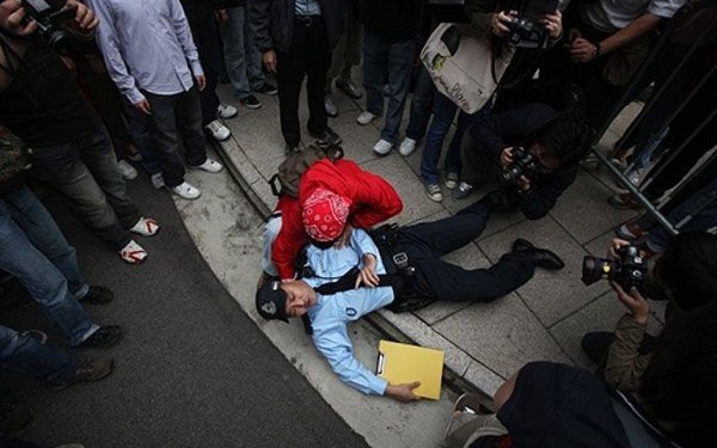 Китай, Гонконг. Поліцейський лежить на землі після бійки з демонстрантами під час акції протесту проти нещодавно оголошеного плану державного бюджету, яку провели у Гонконзі. / © AFP