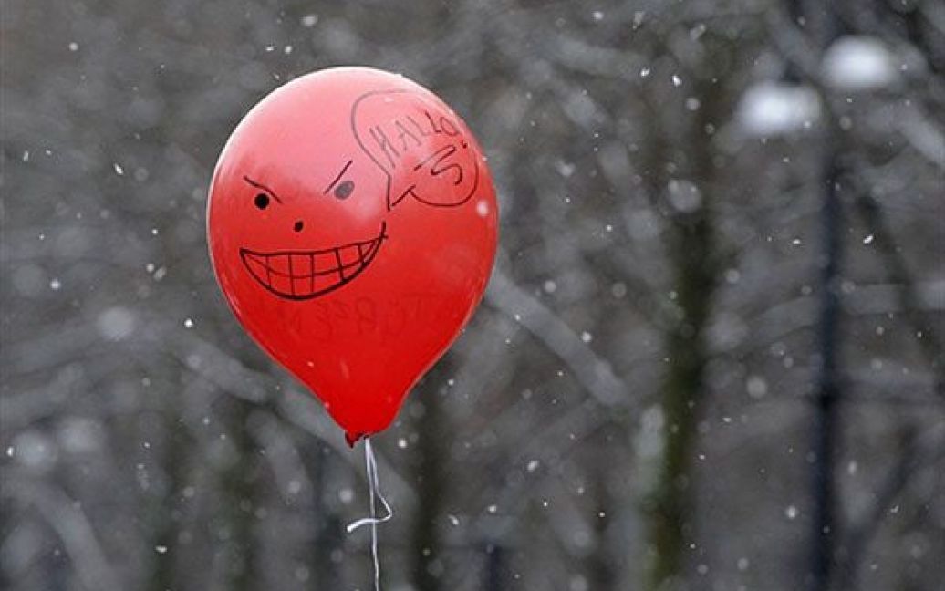 Німеччина, Берлін. Червона повітряна кулька з намальованим на ній усміхненим обличчям висить у повітрі під час акції протесту проти урядових заходів економії, яку провели перед Бранденбурзькими воротами у Берліні. / © AFP