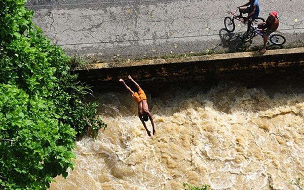 Венесуела, Барловенто. Підліток стрибає у річку у місті Барловенто, штат Міранда. Проливні дощі стали причиною загибелі щонайменше 31 людини. Венесуела потерпає від найстрашнішої повені за останні 40 років. Влада створила 319 притулків для постраждалих від повені по всій країні, без даху над головою залишилися майже 72000 осіб. / © AFP