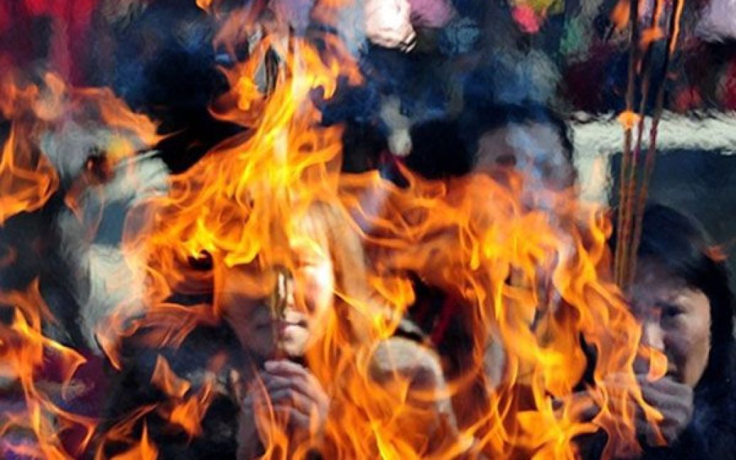 Китай, Пекін. Люди запалюють ароматичні свічки під час молитви у даоському храмі у Пекіні в перший день Нового року за місячним календарем. / © AFP