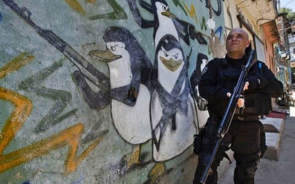 Бразилія, Ріо-де-Жанейро. Озброєний поліцейський стоїть на сторожі під
час рейду у нетрях Алемао в Ріо-де-Жанейро. / © AFP