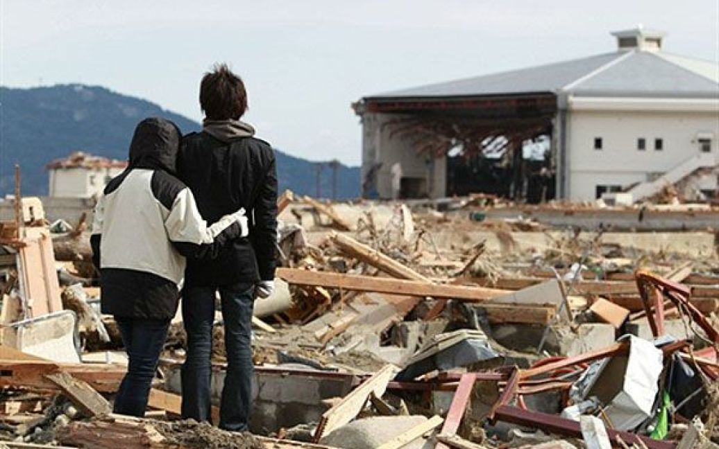 Японія, Рікузентаката. Хлопець з сестрою стоять перед їхнім зруйнованим цунамі будинком у місті Рікузентака, префектура Івате. / © AFP