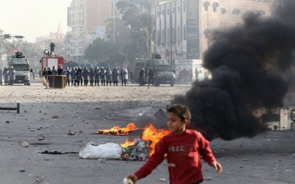 Єгипет, Суец. Дитина пробігає повз палаючі шини, доки поліцейські розганяють демонстрантів під час акції протесту в місті Суец. / © AFP