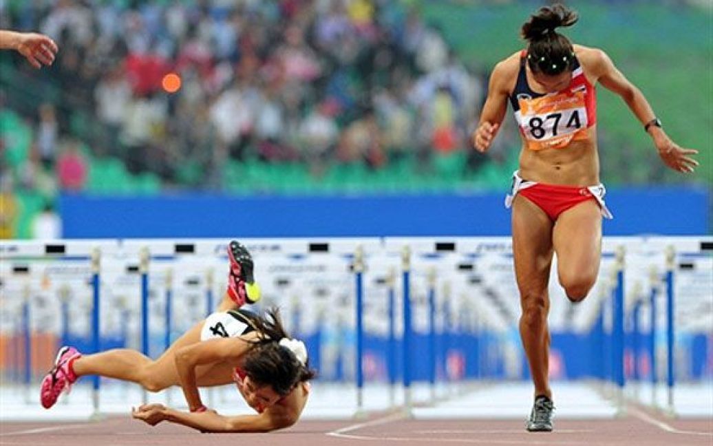 Китай, Гуанчжоу. Японська легкоатлетка Рена Йошита падає на землю на фініші поруч із Валлапою Пансунгнеуен з Таїланду під час забігу на 100 м з перешкодами серед жінок на Азіатських іграх у Гуанчжоу. / © AFP