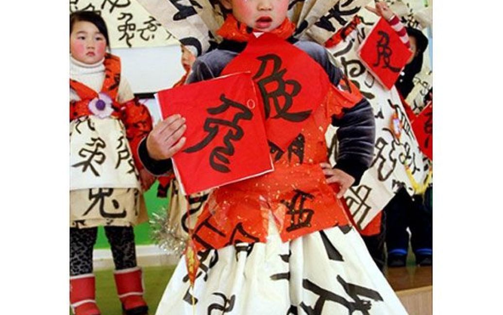 Китай, Ханшан. Китайська дівчина позує поруч із плакатом, на якому зображено китайський ієрогліф "кролик", під час конкурсу каліграфії напередодні святкування місячного Нового року, року Кролика, у школі міста Ханшан, провінція Аньхой. / © AFP