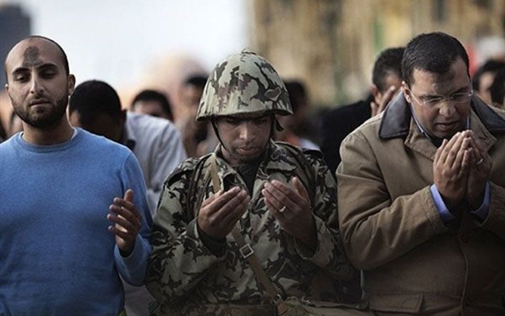 Єгипет, Каїр. Єгипетський військовий приєднався до натовпу демонстрантів-мусульман під час молитви на площі Тахрір у центрі Каїра. По всій країні протягом тижня тривають масові протести. Єгиптяни закликають президента Хосні Мубарака піти у відставку. / © AFP