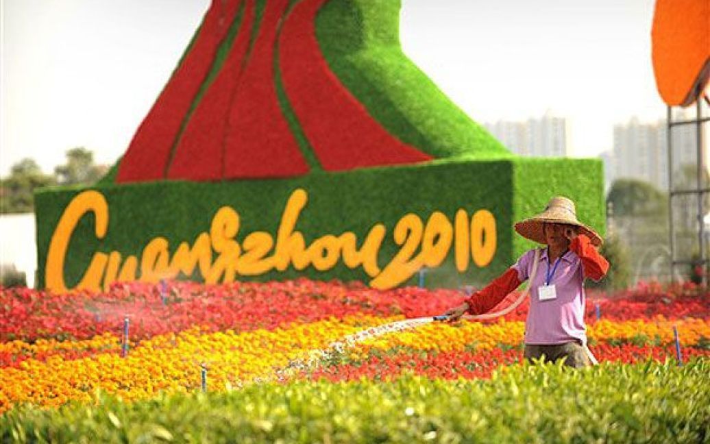 Китай, Гуанчжоу. Працівник поливає квіти поблизу місця проведення церемонії відкриття 16-их Азіатських ігор у Гуанчжоу. / © AFP