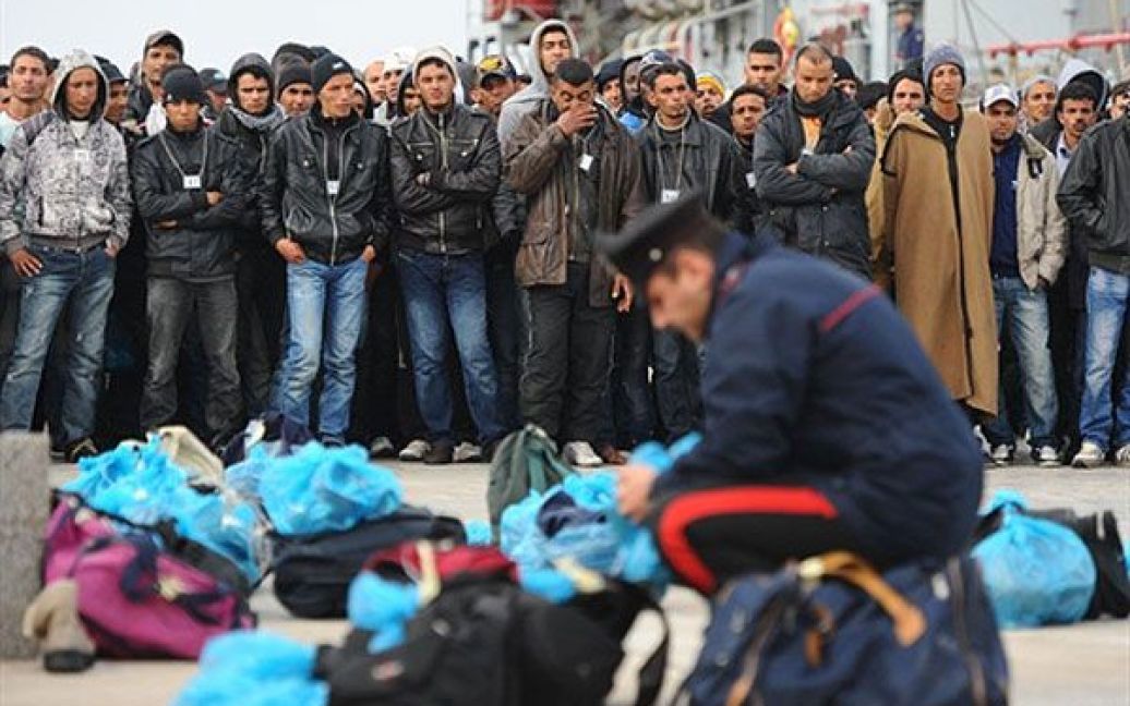 Італія, Лампедуза. Поліцейські перевіряють речі туніських потенційних іммігрантів після прибуття до Лампедузи. Італійський корабель "Спіка" врятував 129 потенційних мігрантів у морі поблизу Лампедузи. / © AFP