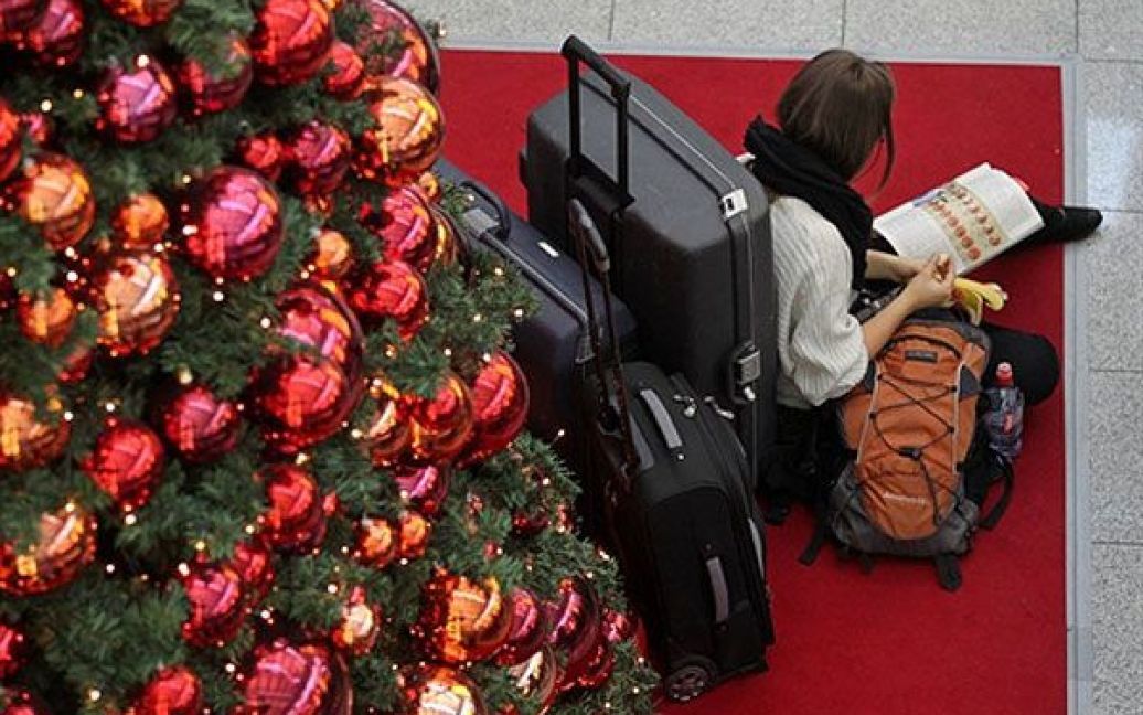 Німеччина, Дюссельдорф. Пасажирка сидить і читає під різдвяною ялинкою, очікуючи на літак в аеропорту міста Дюссельдорф. / © AFP
