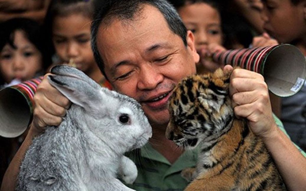 Філіппіни, Маніла. Власник зоопарку "Малабон" Менні Тангко тримає в руках кролика і тигреня, які ілюструють перехід від року Тигра до року Кролика. У Китаї та багатьох інших частинах Азії у лютому 2011 року відзначатимуть початок року Кролика за китайським календарем. / © AFP