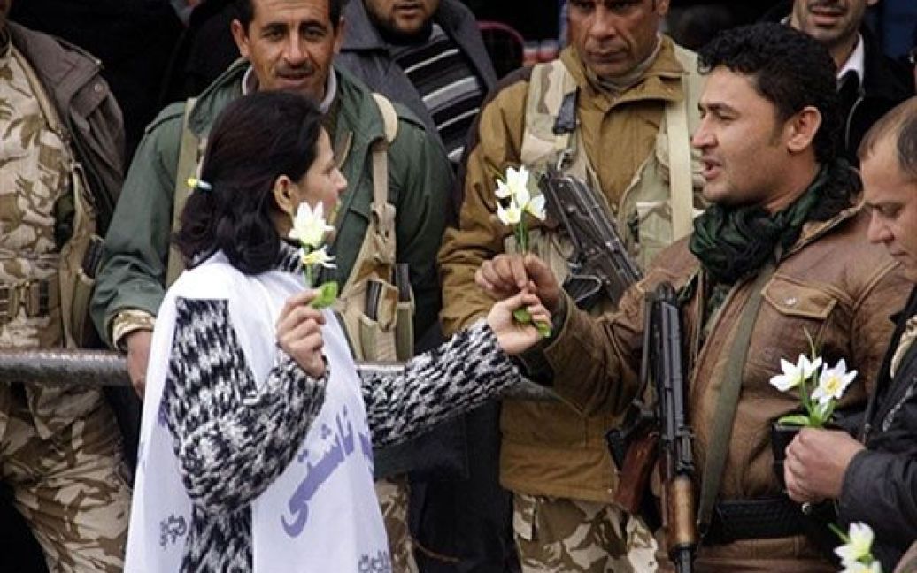 Ірак, Сулейманія. Жінка роздає квіти солдатам під час акції, коли митці та інтелігенція побудували уявну стіну миру між демонстрантами та силами безпеки для запобігання насильству на головній площі Сулейманії. Тисячі людей закликали до проведення політичної реформи. / © AFP