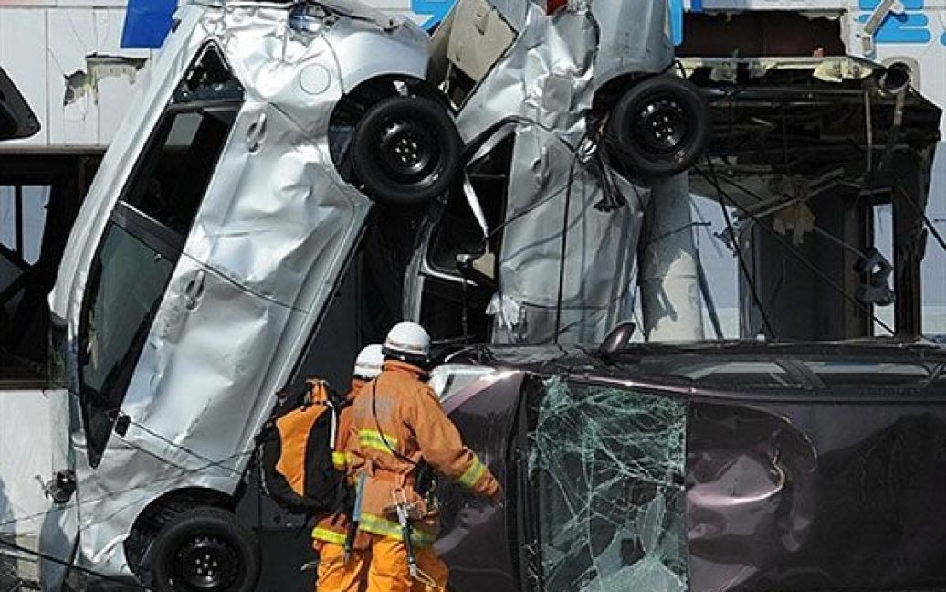 Японія, Сендай. Рятувальники проходять повз автомобілі, перевернуті хвилею цунамі. В Японії стався найсильніший за всю історію країни землетрус, який спричинив потужні хвилі цунамі. / © AFP