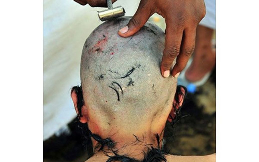 Саудівська Аравія, Мекка. Паломник-мусульманин голить голову після виконання ритуалу "Джамарат", символічного побиття камінням Сатани, який він здійснив у Міні, поблизу священного міста Мекки на третій день хаджу. / © AFP